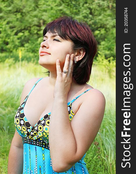 Young beautiful contented dreamy woman on nature