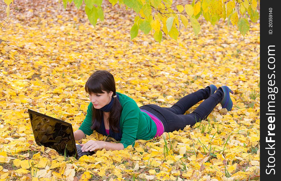 Young girl with a laptop in a autumn foliage