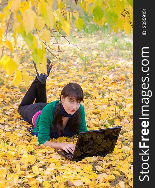 Young girl with a laptop in a autumn foliage