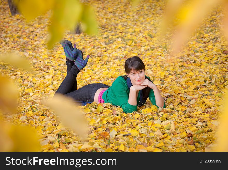 Beautiful girl with dark hair resting on yellow autumn leaves. Beautiful girl with dark hair resting on yellow autumn leaves