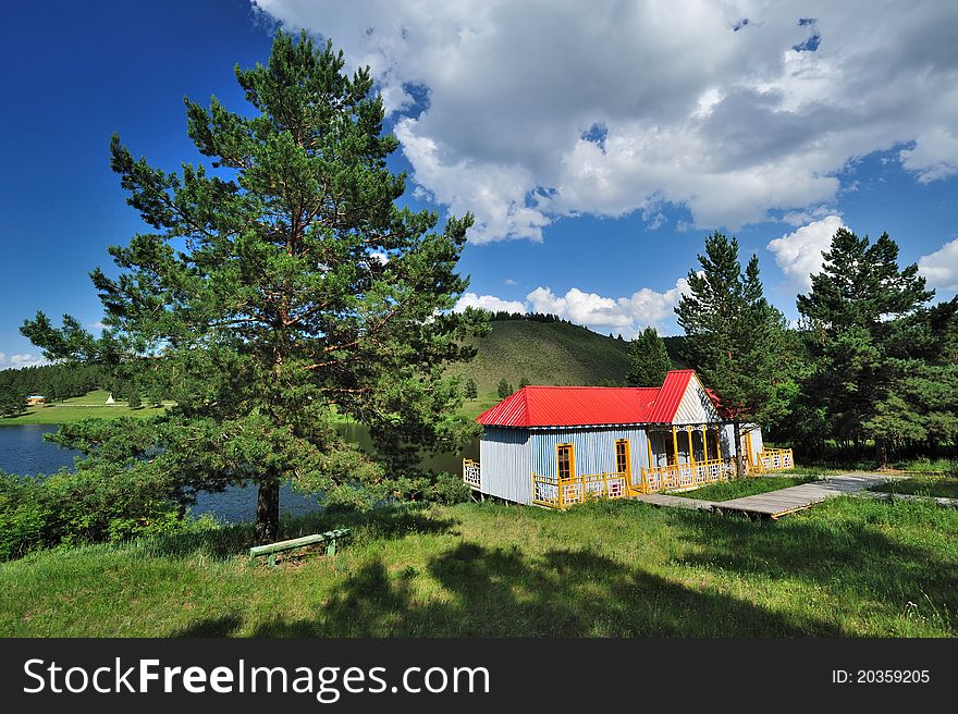 Log Cabin under blue sky and white clouds along the lake. Log Cabin under blue sky and white clouds along the lake.