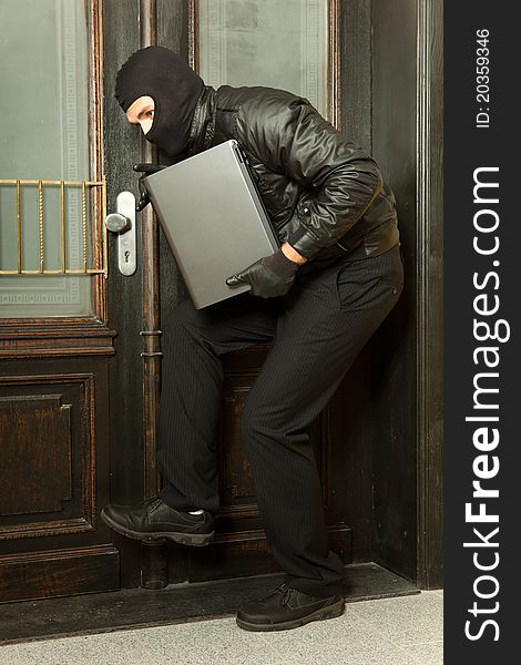 Gangster steals a laptop in front of a door