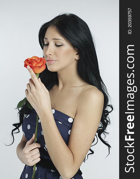 Romantic pretty brunette in polka dot dress holding a rose. Romantic pretty brunette in polka dot dress holding a rose