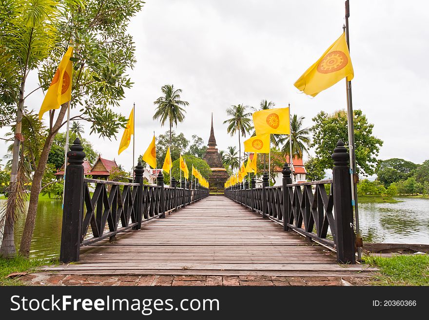 Wooden bridge to ruin pagoda with buddhist flag in Sukhothai
