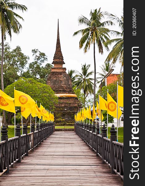 Wooden bridge to ruin pagoda with buddhist flag in Sukhothai (vertical closed up). Wooden bridge to ruin pagoda with buddhist flag in Sukhothai (vertical closed up)