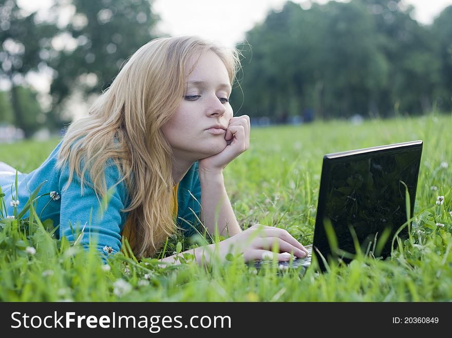 Portrait of pretty woman with laptop on the green grass