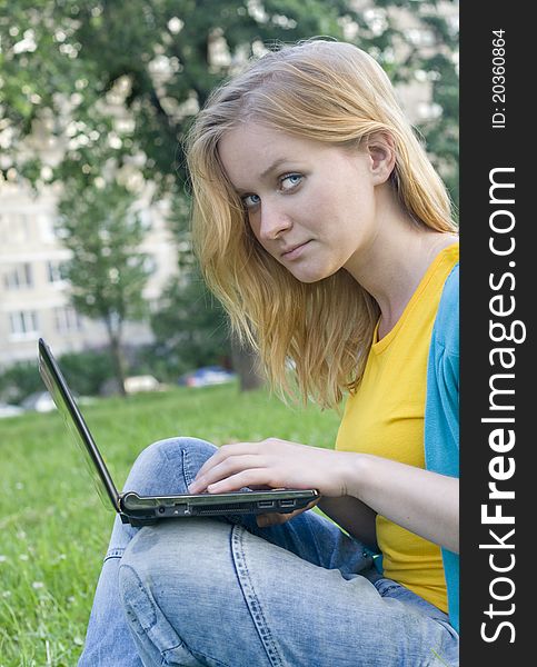 Portrait of pretty woman with laptop on the green grass