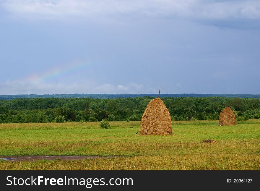 The haystack, the Russian landscape rainbow in the sky after the storm