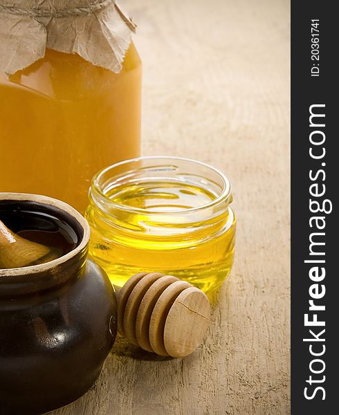 Honey in jars and pot on wood table