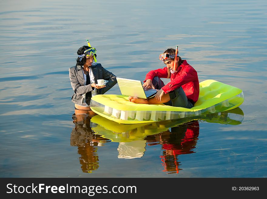 Businessman with notebook sitting on inflatable mattress and his secretary brings coffee to him. Businessman with notebook sitting on inflatable mattress and his secretary brings coffee to him.