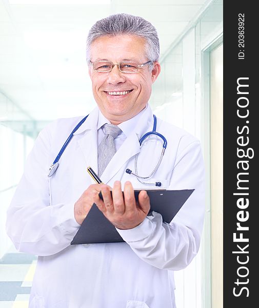 Closeup portrait of a happy young doctor with stethoscope in hospital writing a receipt. Closeup portrait of a happy young doctor with stethoscope in hospital writing a receipt