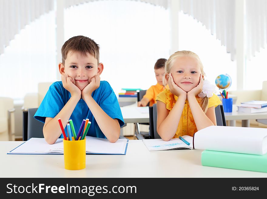 Boy and girl sitting together at a desk at school.