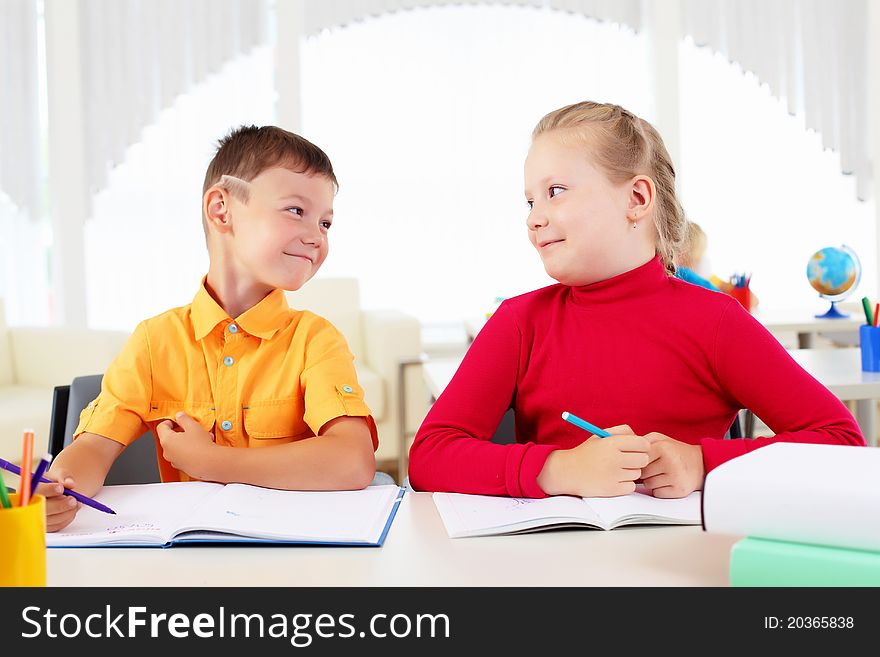 Boy and girl sitting together at a desk at school.