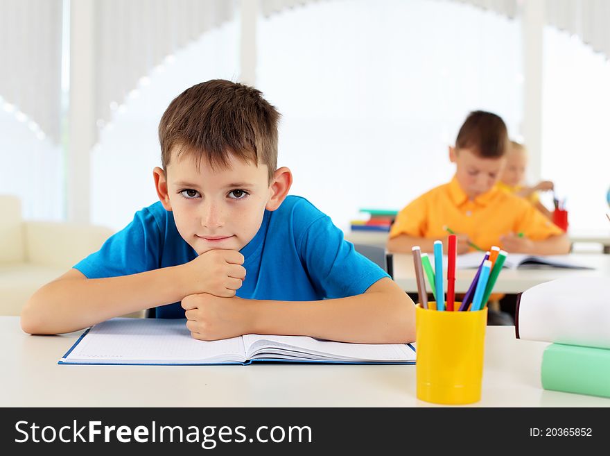 Portrait of a young boy sitting at his desk at school