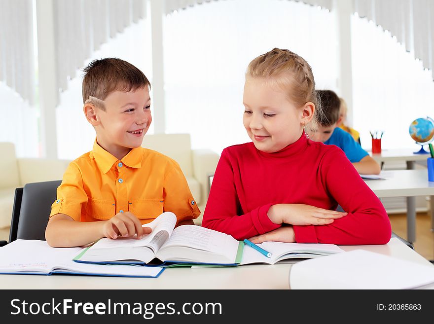 Boy and girl sitting together at a desk at school.