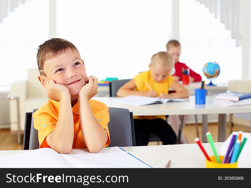 Portrait of a young boy sitting at his desk at school