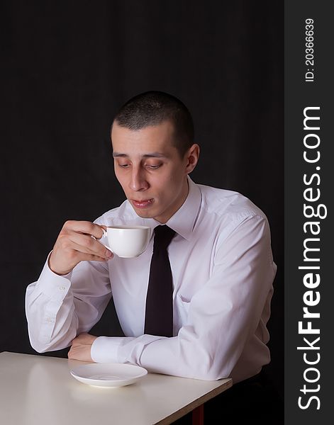 Bored businessman with cup of coffee isolated on black