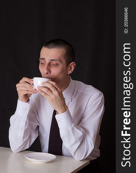 Bored businessman with cup of coffee isolated on black