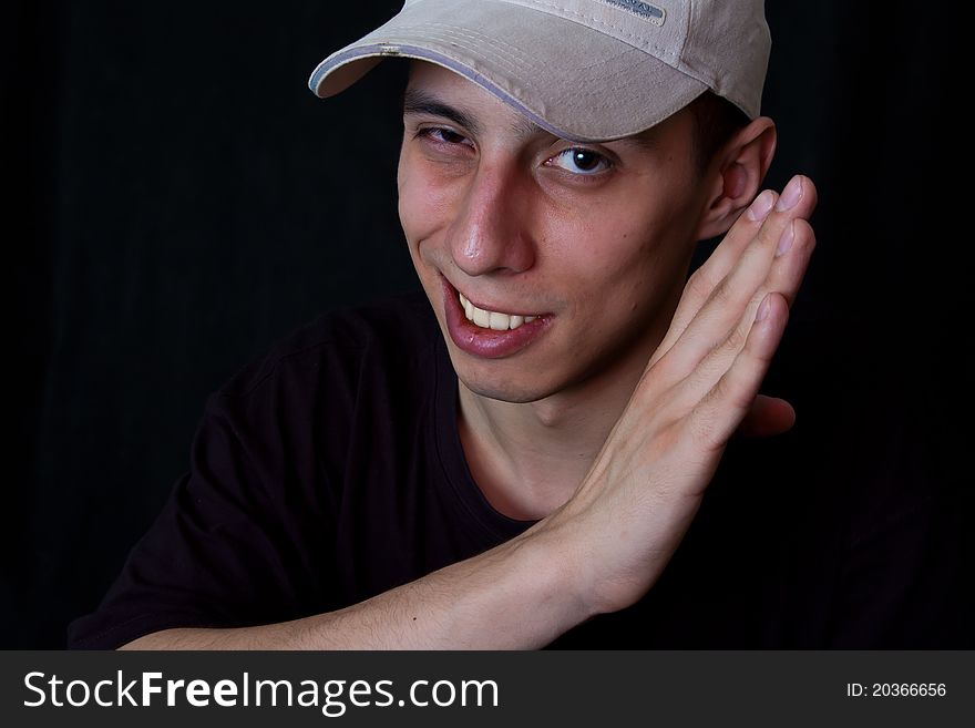 Portrait of grinning man in cap on black