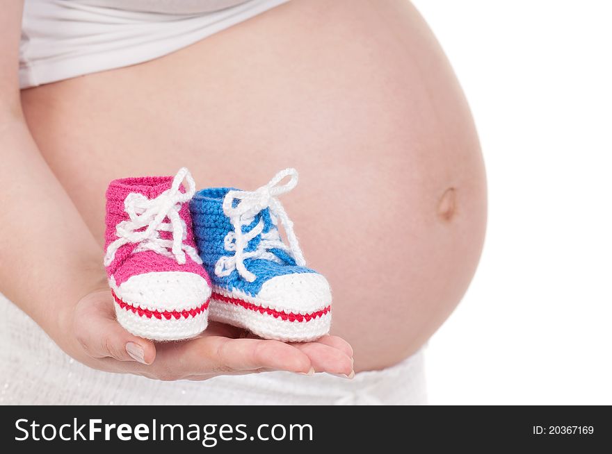 Pregnant woman holding a baby's bootees in different colours. Pregnant woman holding a baby's bootees in different colours