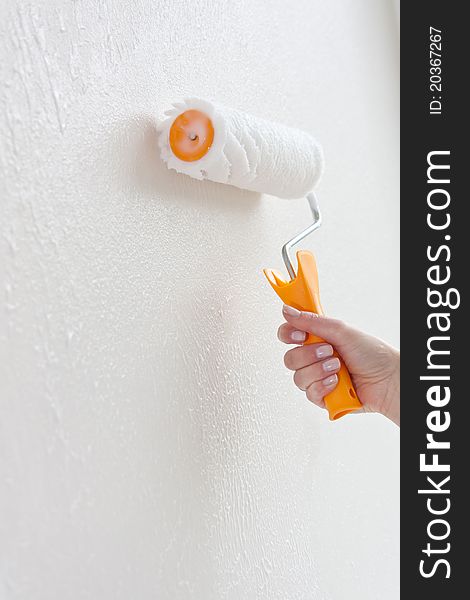 Putting glue on th a white wall with a paint roller. Putting glue on th a white wall with a paint roller
