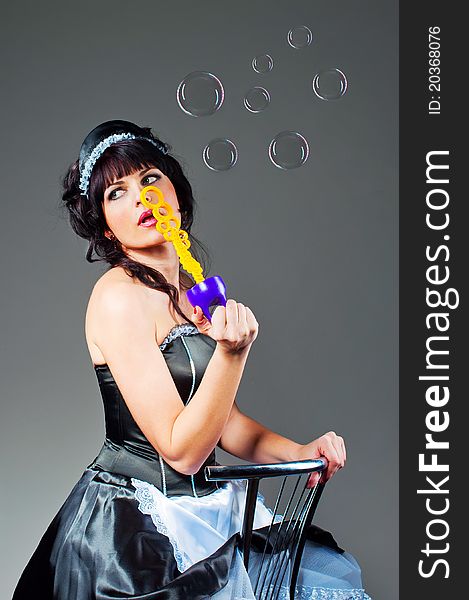 Portrait of young woman inflating soap-bubbles in studio