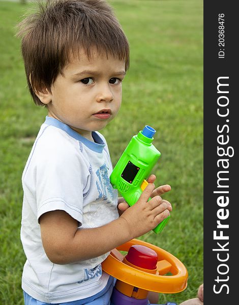 Adorable two year old boy playing with gun outside. Adorable two year old boy playing with gun outside