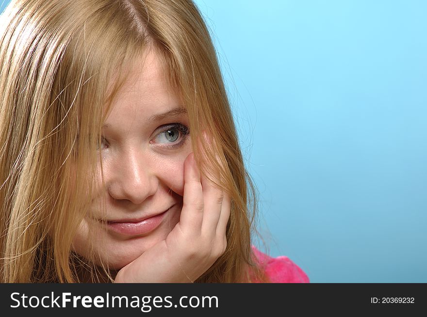 Young woman with cheesy smile; close-up shot in studio against blue background. Young woman with cheesy smile; close-up shot in studio against blue background