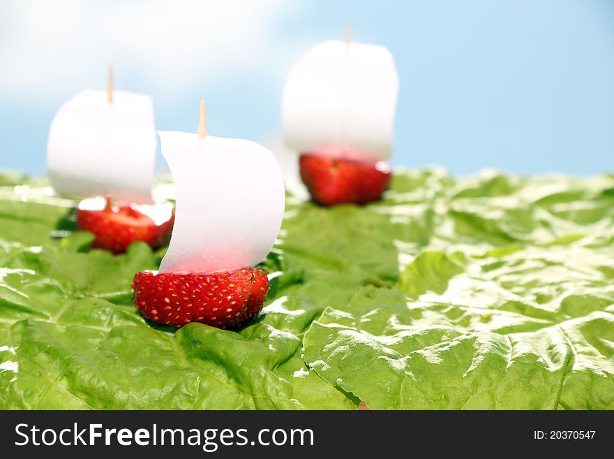 Boats, made of fresh strawberries on lettuce leaves