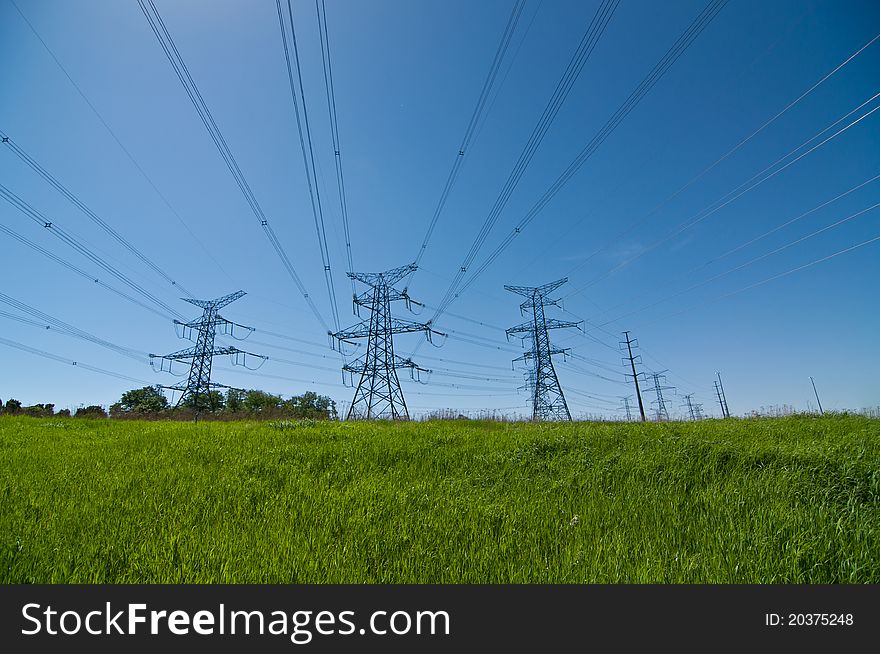 A long line of electrical transmission towers carrying high voltage lines. A long line of electrical transmission towers carrying high voltage lines.