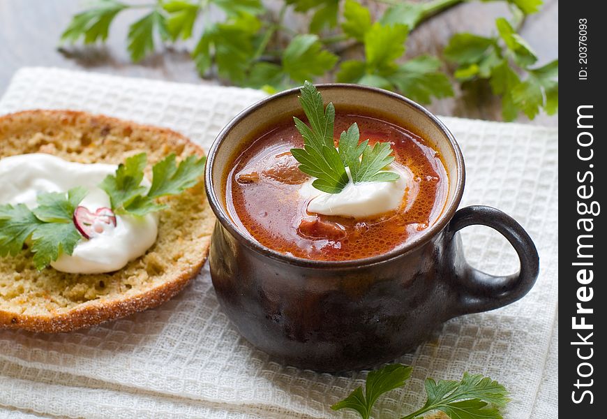 A cup of vegetable soup with sour cream and parsley. Selective focus