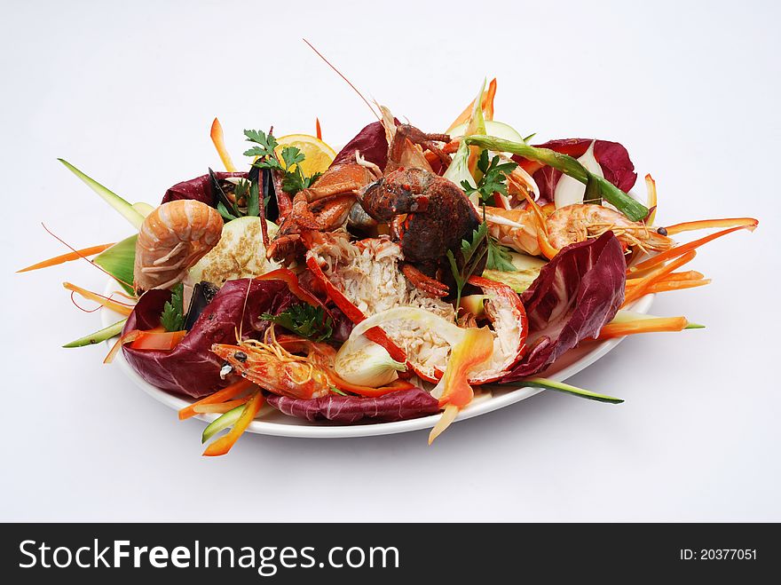 Fantasy fish with king prawns with vegetables served on a plate on a white background
