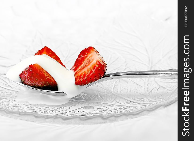 Red strawberry and white ice cream on spoon on white background