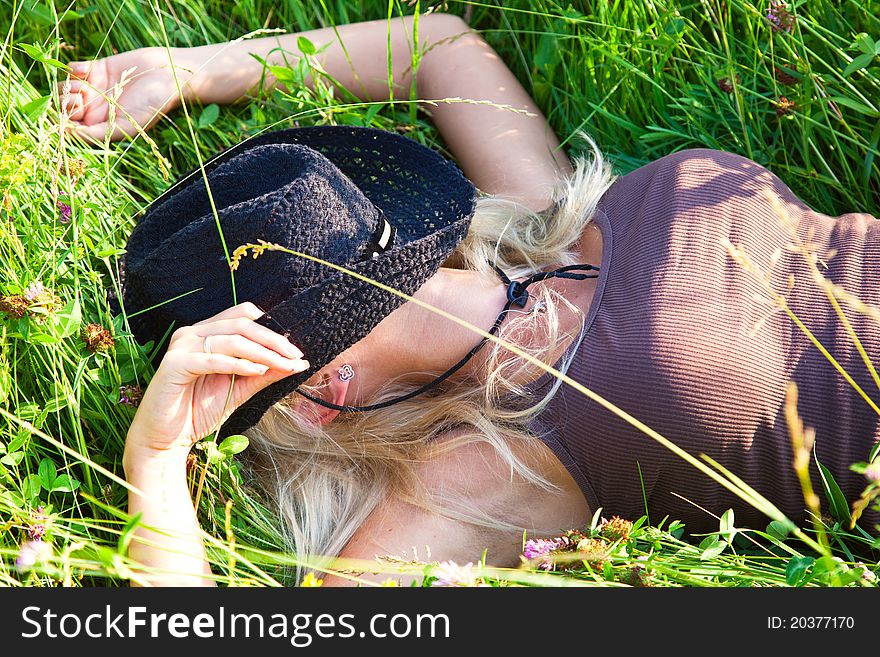 Young blond cowgirl lying in grass. Young blond cowgirl lying in grass