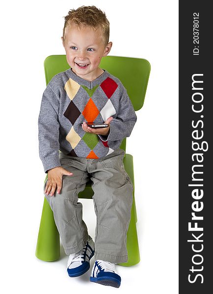 Happy boy with a smart phone sitting on a chair - isolated