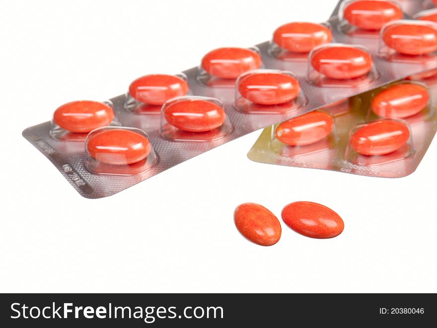 Close up orange capsules and blisters isolated on white