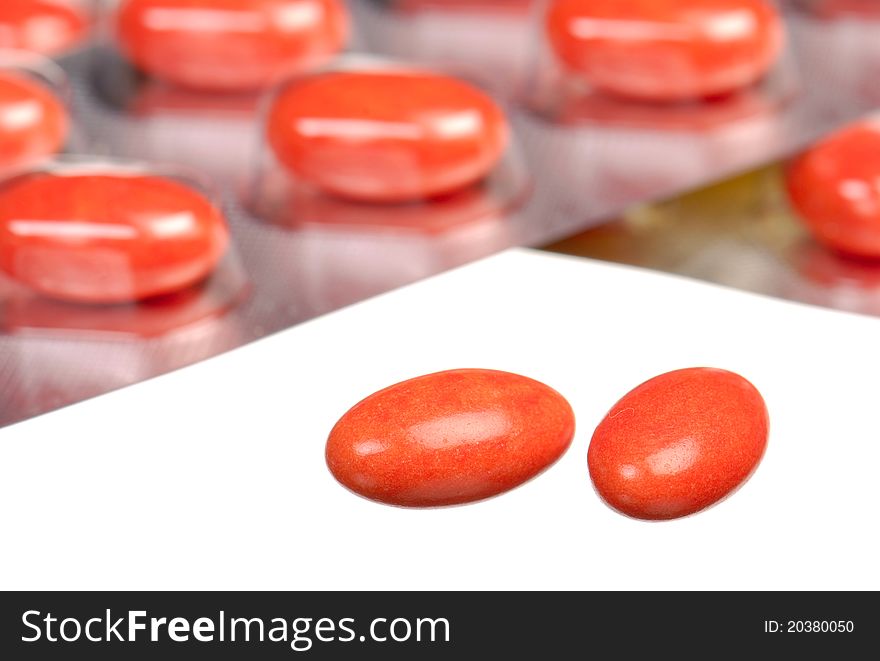 Close up orange capsules and blisters isolated on white