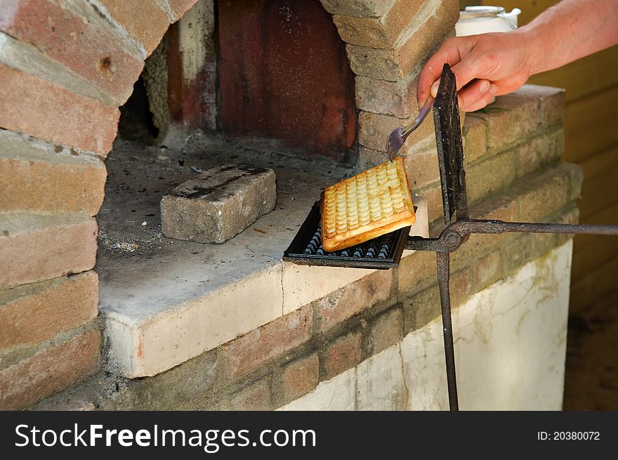 Baking authentic brussels waffels in with a waffle- iron in a wood fired oven. Baking authentic brussels waffels in with a waffle- iron in a wood fired oven