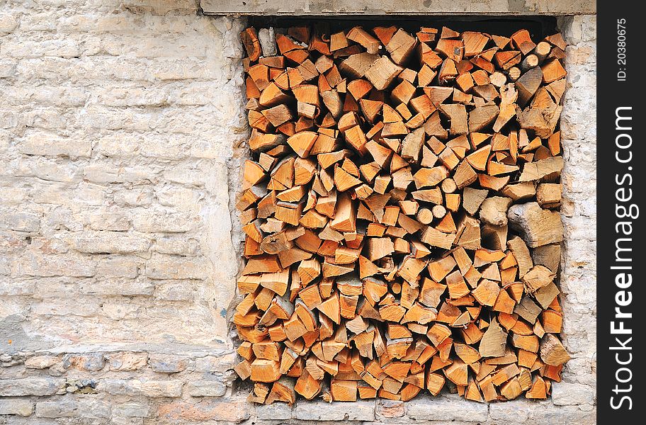 Pile of chopped fire wood prepared for winter. Old house wall