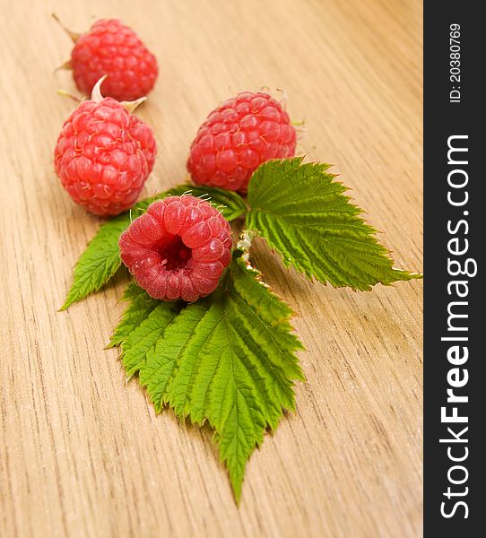 Ripe raspberries with leaves on the table