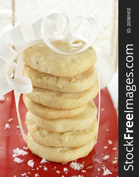 Stack of white ribboned shortbread cookies; fake snow on cookie tray. Stack of white ribboned shortbread cookies; fake snow on cookie tray