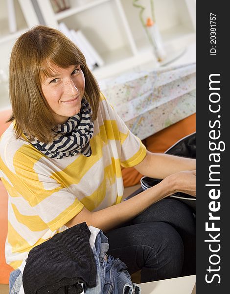 Smiling woman packing for travel at home