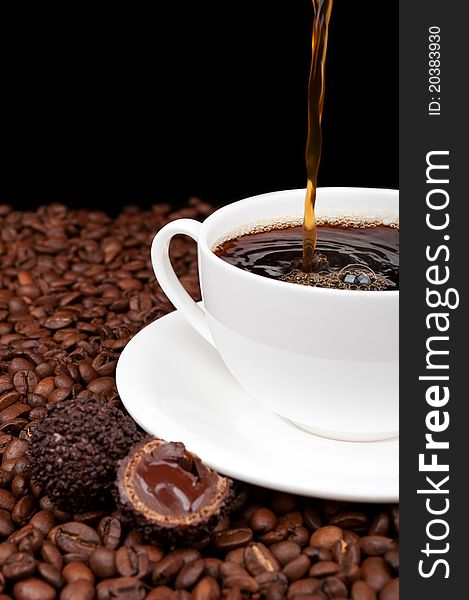 White cup with coffee and coffee beans on a black background. White cup with coffee and coffee beans on a black background