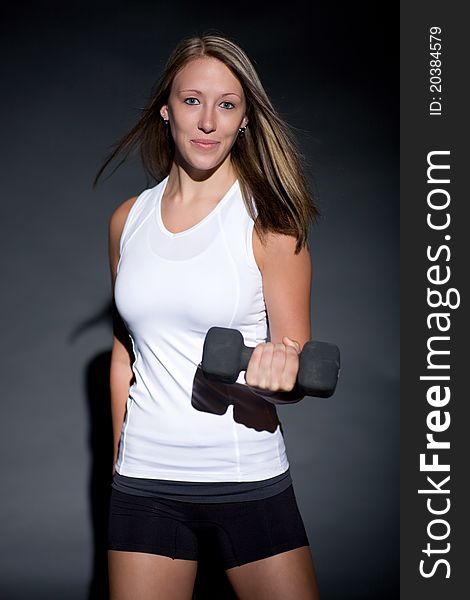 Young woman poses wearing workout outfit and holding dumbbell. Young woman poses wearing workout outfit and holding dumbbell.