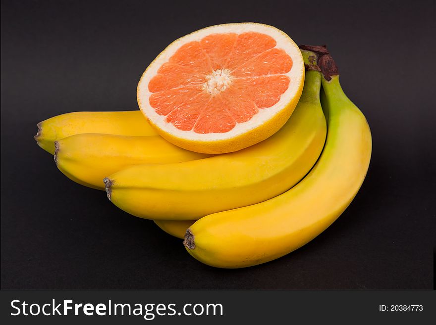 Grapefruit and banana on black background