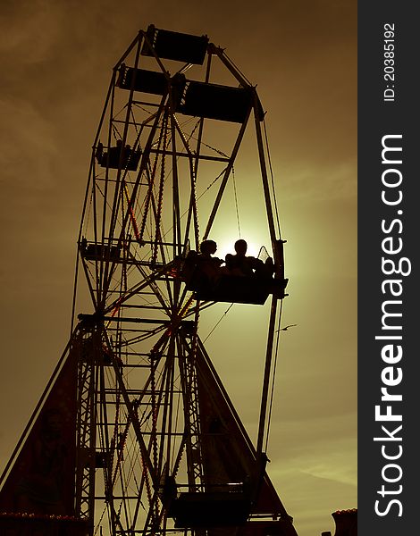 Couple riding in funfair wheel at sunset