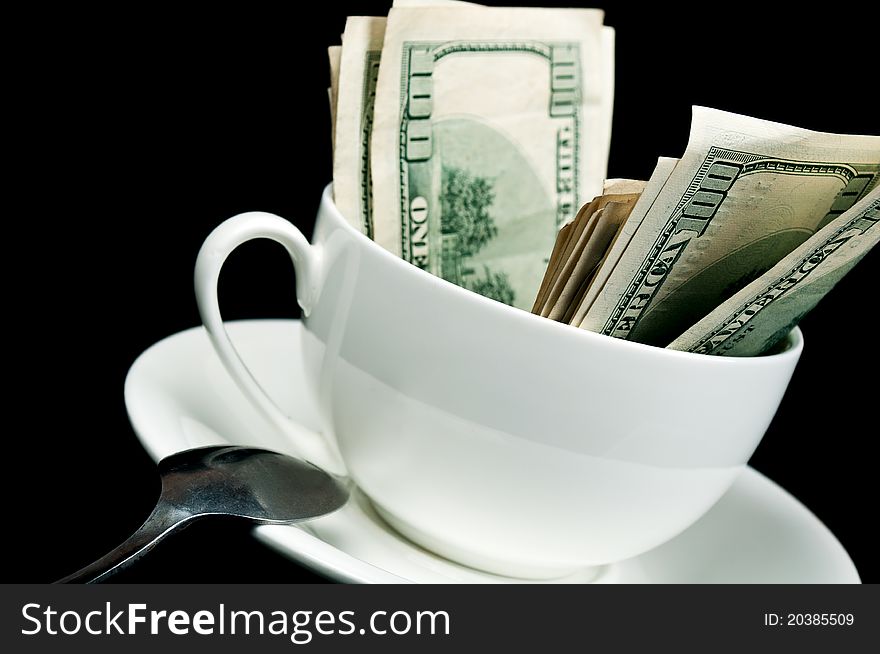 White cup full of dollars isolated on a black background