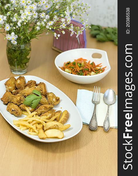 Golden fried chicken and fried potatoes in a white plate on the table