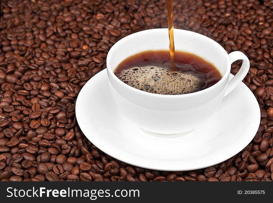 White cup with coffee and coffee beans on a background