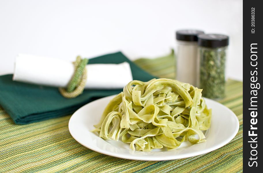 Plate of green spinach pasta fettuccine on served table. Plate of green spinach pasta fettuccine on served table